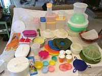 Wide view of the vintage plastic kitchenware collection showing all items on a white sheet. Includes containers, salad spinners, bowls, and accessories.