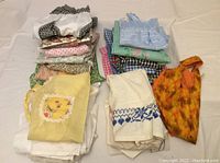 Top view of folded aprons and bib laid out showing various patterns and colors such as yellow, blue, green, pink, and orange.