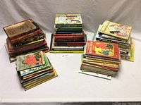 Wide shot of multiple stacks of vintage children's books showing a range of titles and cover conditions