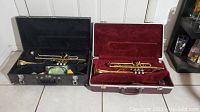 Two brass trumpets in cases, King trumpet in black case on left, Jupiter trumpet in red case on right, showing overall view of lot.