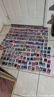 Over 200 Yu-Gi-Oh! trading cards laid out on the floor, showing front faces with various designs and colors representing monster, spell, and trap cards.