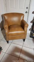 Full front view of camel color club chair showing overall condition and shape.