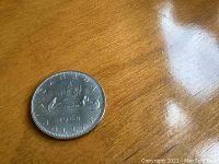 Front side of 1969 Canadian one dollar coin showing the voyageur design with canoe and inscription.