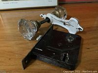 Pair of crystal glass doorknobs attached to white ornate backplates with black metal mortise lock on wooden surface.