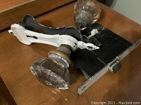 Two antique glass door knobs with metal backplates and attached metal latch mechanism displayed on wooden surface