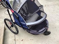 Side view of the blue Schwinn bike trailer showing mesh sides, padded interior, and wheel assemblies.