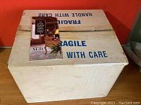Closed cardboard box labeled fragile with a marketing brochure for Living Air XL-15 on top.