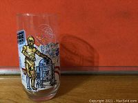 Tall glass tumbler showing front view of printed artwork featuring C-3PO and R2-D2 robotic characters from Star Wars.