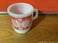Photo showing Fire King white opaque glass mug with orange band and daisy floral design on one side