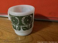 Side view of Fire King coffee mug showing green floral pattern on white opaque glass.