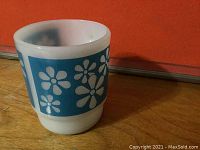 Front angle showing white mug body with blue floral design.