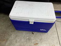 Top closed view of the large blue and white Igloo cooler with latch and measuring marks on lid.