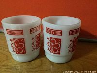 Two white opaque mugs with red psychedelic floral and geometric designs.
