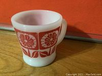White ceramic mug with red sunflower pattern, showing side view and handle.