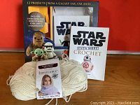 Photo showing two Star Wars crochet pattern books in original packaging with images of Yoda and Stormtrooper, and included white skein of yarn.