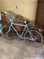 Overall side view of a white JC Penny men's bicycle with rear rack, headlight, and dry rotted tires