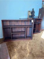 Front view of two wooden bookcases side by side showing stationary shelves and scratched wood surfaces.