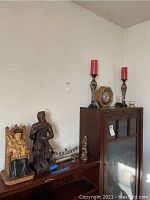 Wide shot showing entire lot including candle holders, clock, two figurines, and menorahs on wooden sideboard