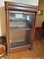 Front view of the wood display cabinet showing glass door and wood frame with visible scratches and wear.