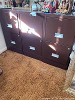 Full view of three brown metal two-drawer filing cabinets placed side by side on carpeted floor with various decorative items on top.