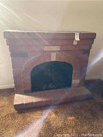 Front view of faux brick fireplace showing the arched opening and electric insert inside.