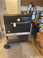 Full view of Char-Broil charcoal grill showing black metal body, wood handle on lid, front door, bottom shelf, and wheels.