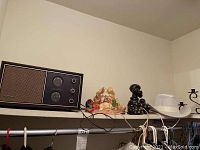 Photo showing Concord vintage radio with two dials and speaker, alongside small decorative animal figurines and a white mesh hat.