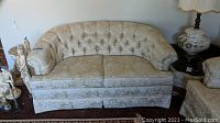 Full view of the beige floral patterned, tufted back Hickory Hill love seat.