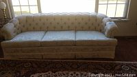 Front view of the sofa showing tufted back, rolled arms, and three seat cushions.