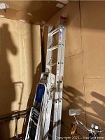 Photo showing two aluminum ladders and one step stool against a wall, highlighting overall size and condition.