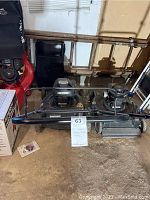 Overall side view of the Bolens black lawn mower with collection bag next to it, showing the mowing deck and engine.