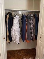 Wide view of closet showing a variety of jackets and sweatshirts hanging on hangers on a rod.