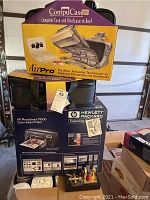 Photo showing stacked items: purple CompuCase AirPro computer bag on top, black computer bag below, and boxed HP PhotoSmart P1000 printer at bottom.