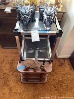 Full view of chrome and glass shelves with dragon figurines on top, wooden bunny figurine and bell on smaller wooden corner shelf below