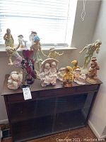 Photo showing full collection of Dreamsicles figurines and statues arranged on dark wood table under window light.