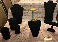 Photo showing the velvet bust necklace displays, ring holders, bracelet holder, and wood backdrop including leopard print detail and gold wood stand.