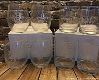 Eight glasses arranged in two rows on a wooden surface in front of a brick background. Four snowflake tumblers and four Parx Casino logo on the rocks glasses on their original boxes.