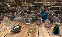 Full view of the lot showing multiple Murano glass animal figurines and paperweights arranged on wooden surface with brick background
