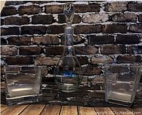 Photo showing a clear glass decanter with a stopper flanked by two small square glass vases, all vintage and in excellent condition.