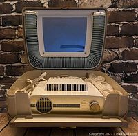 Vintage Ronson Escort hair dryer in beige case with attached flexible hose and mirror in lid, showing the unit and storage compartments.