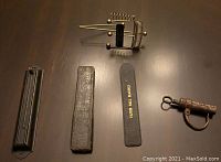 Lot of four vintage items arranged on a dark surface: a French lock, Congress razor in box, Fafnir ball bearing file, small metal clip.