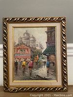 Framed oil on board painting showing a European street scene with people walking and architecture in background, signed by the artist.