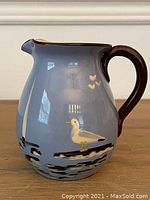 Overall view of the hand painted Babbacombe Torquay Devon England pitcher featuring seagull motifs on blue glaze with dark brown handle.