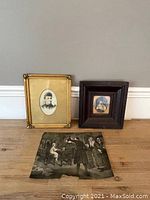 Image showing two framed portraits and one vintage print on the floor against a wall.