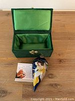 Green velvet-lined original box with open lid alongside the ornament and instruction card.