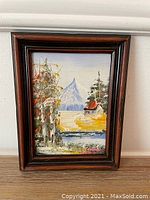 Framed oil on board landscape painting showing autumn foliage, river, cabin, and mountain.
