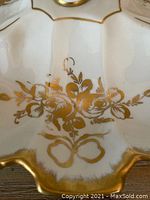 Close-up photo of the porcelain serving dish showing intricate gold floral motif and part of the scalloped edge with gold trim.