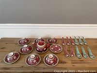Full set arranged including teapot, cups with lids, saucers, and serving spoons in red and turquoise.
