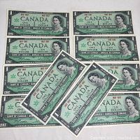 View of ten Canadian Centennial $1 banknotes laid flat and arranged to show the front side featuring Queen Elizabeth II portrait and commemorative text.