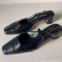 Side and top view of both black leather slingback shoes with low block heels, showing the elegant design and condition.